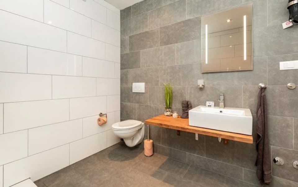 Totalsanierung EFH, Buchs ZH — neu saniertes Badezimmer mit Plattenbelag und moderner Haustechnik